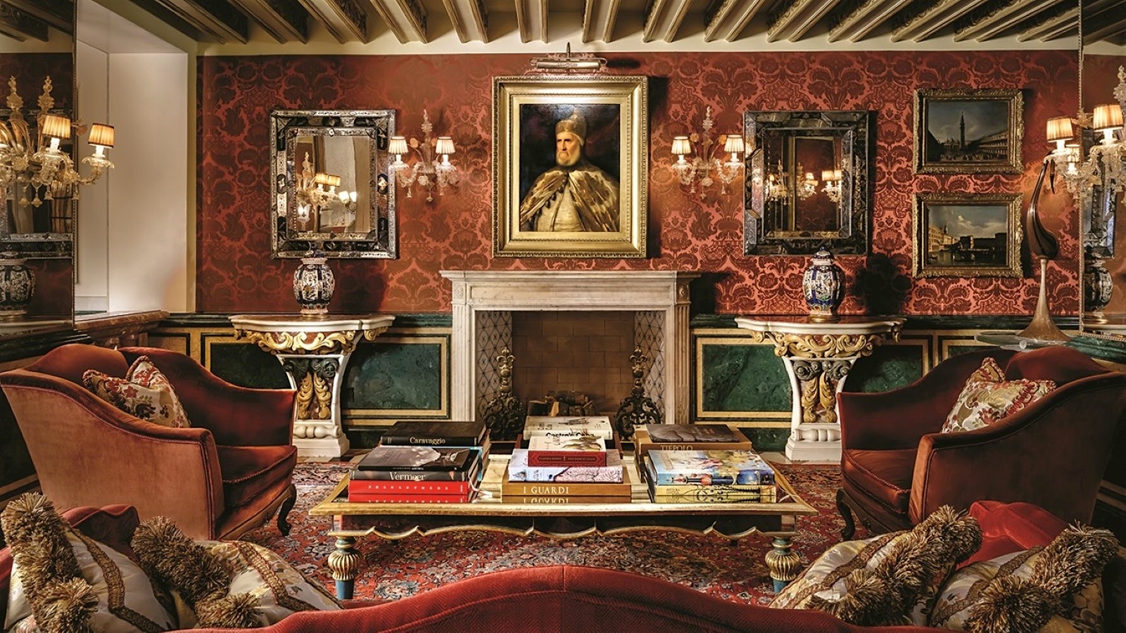 A room at The Gritti Palace with red silk wallpaper, three couches and a portrait of a Doce of Venice
